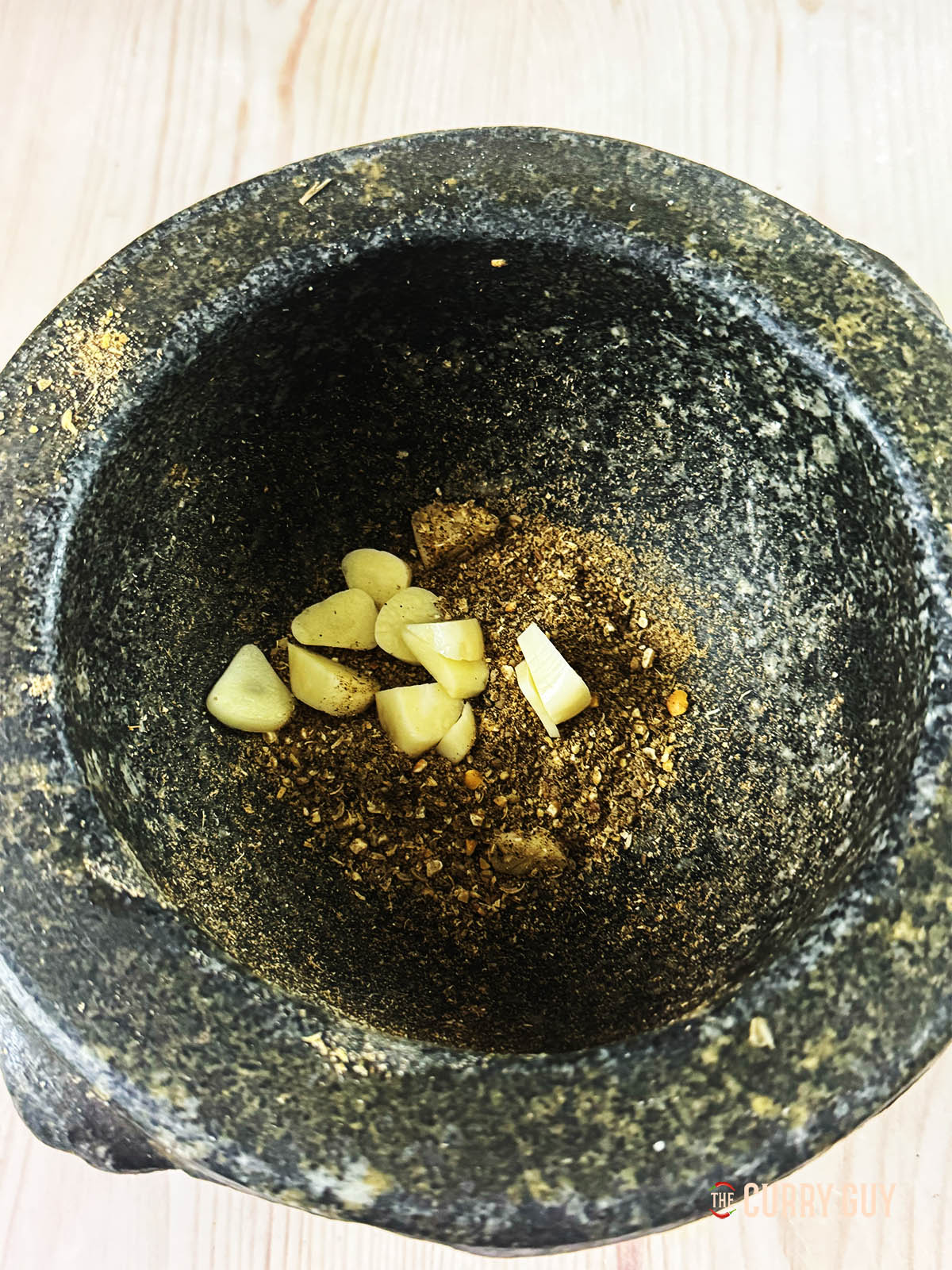 Grinding the whole spices and garlic into a paste.