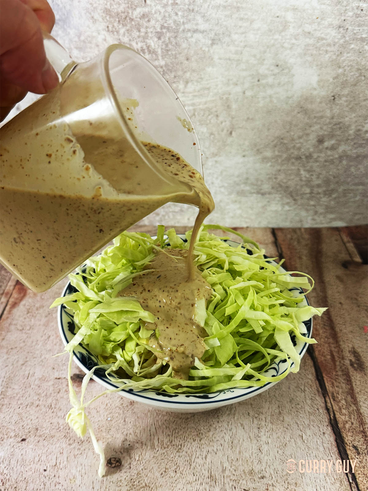 Adding Japanese salad dressing to some cabbage.