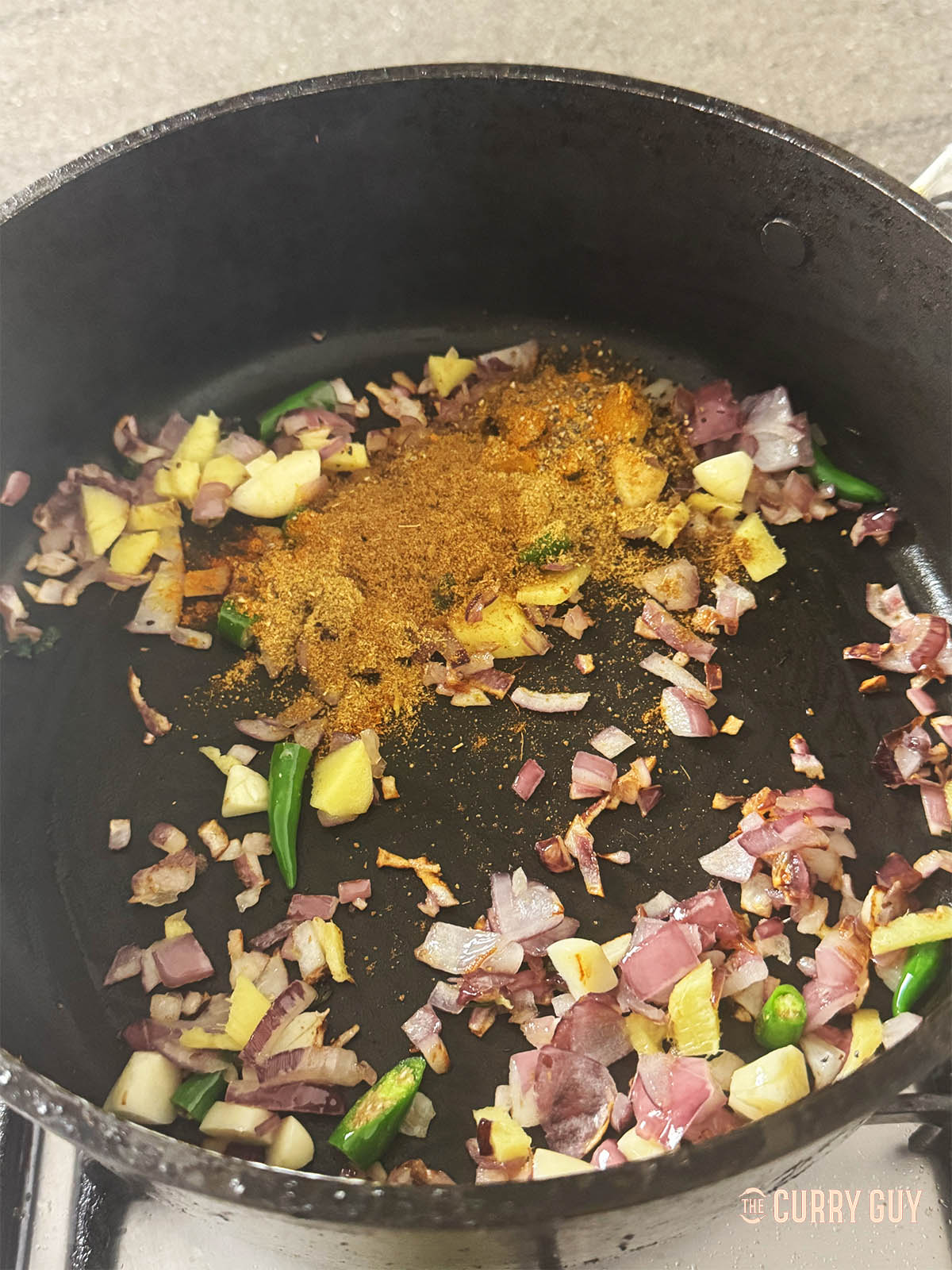 Adding the ground spices to the pan.