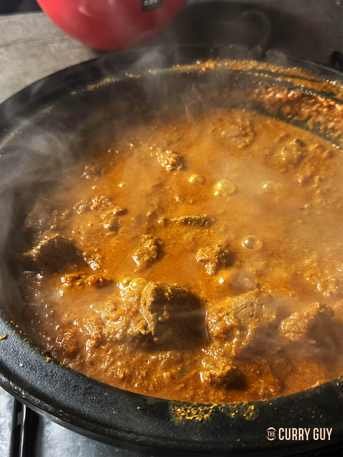 Simmering the venison curry to flavour and tenderise the meat.