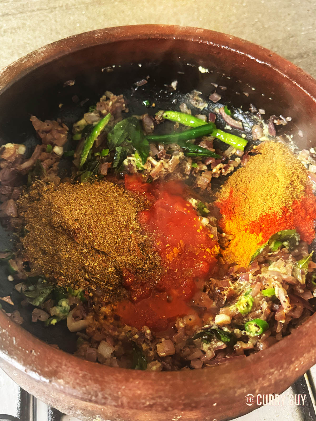 Adding the chopped tomatoes and ground spices to the pan.