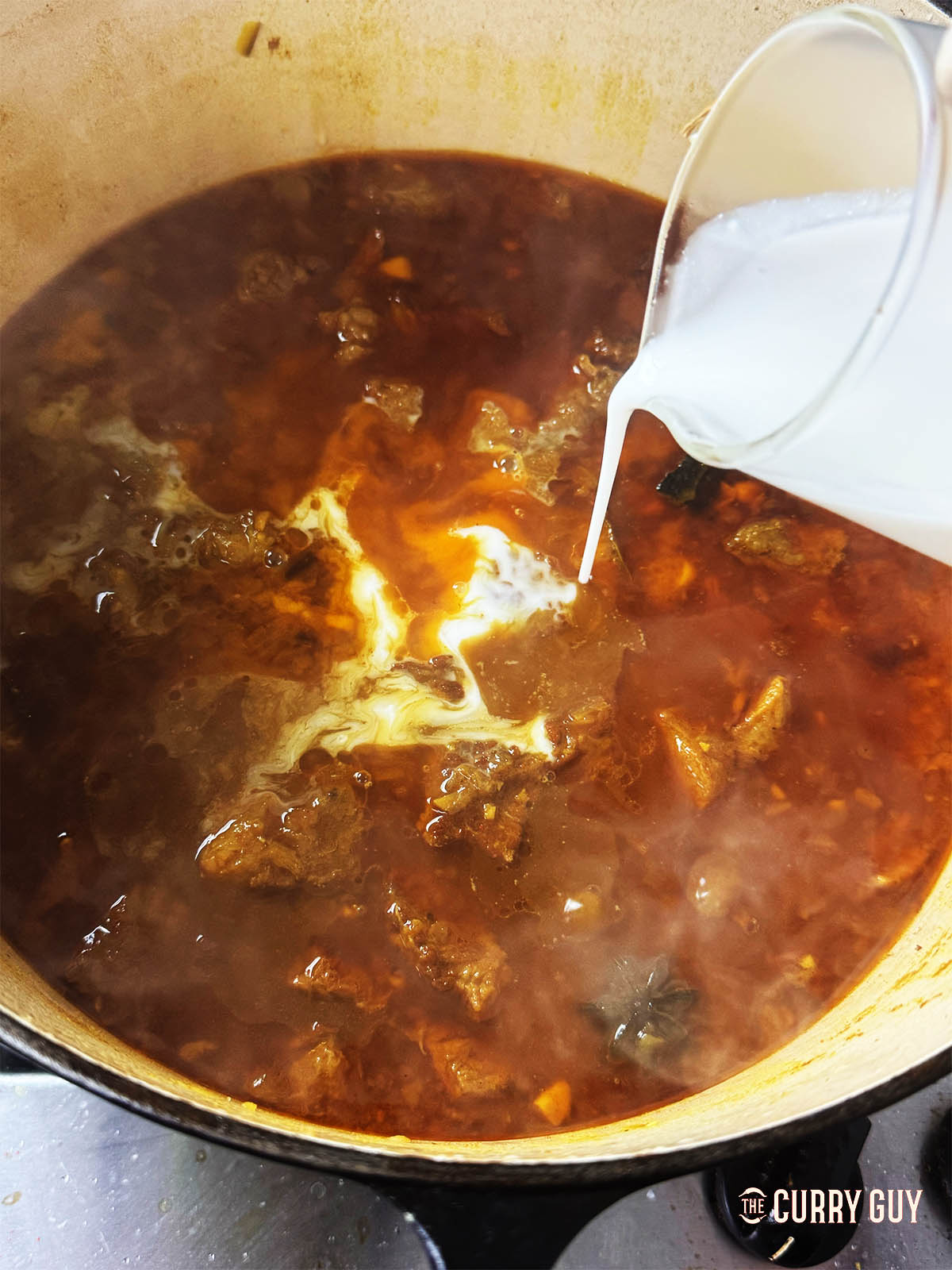 Pouring the coconut milk into the sauce.