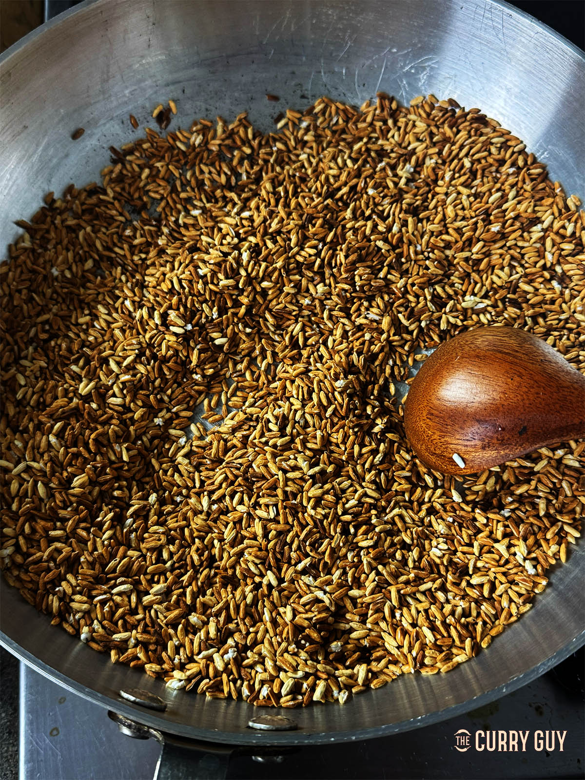 The sticky rice in a pan, golden brown after toasting. 