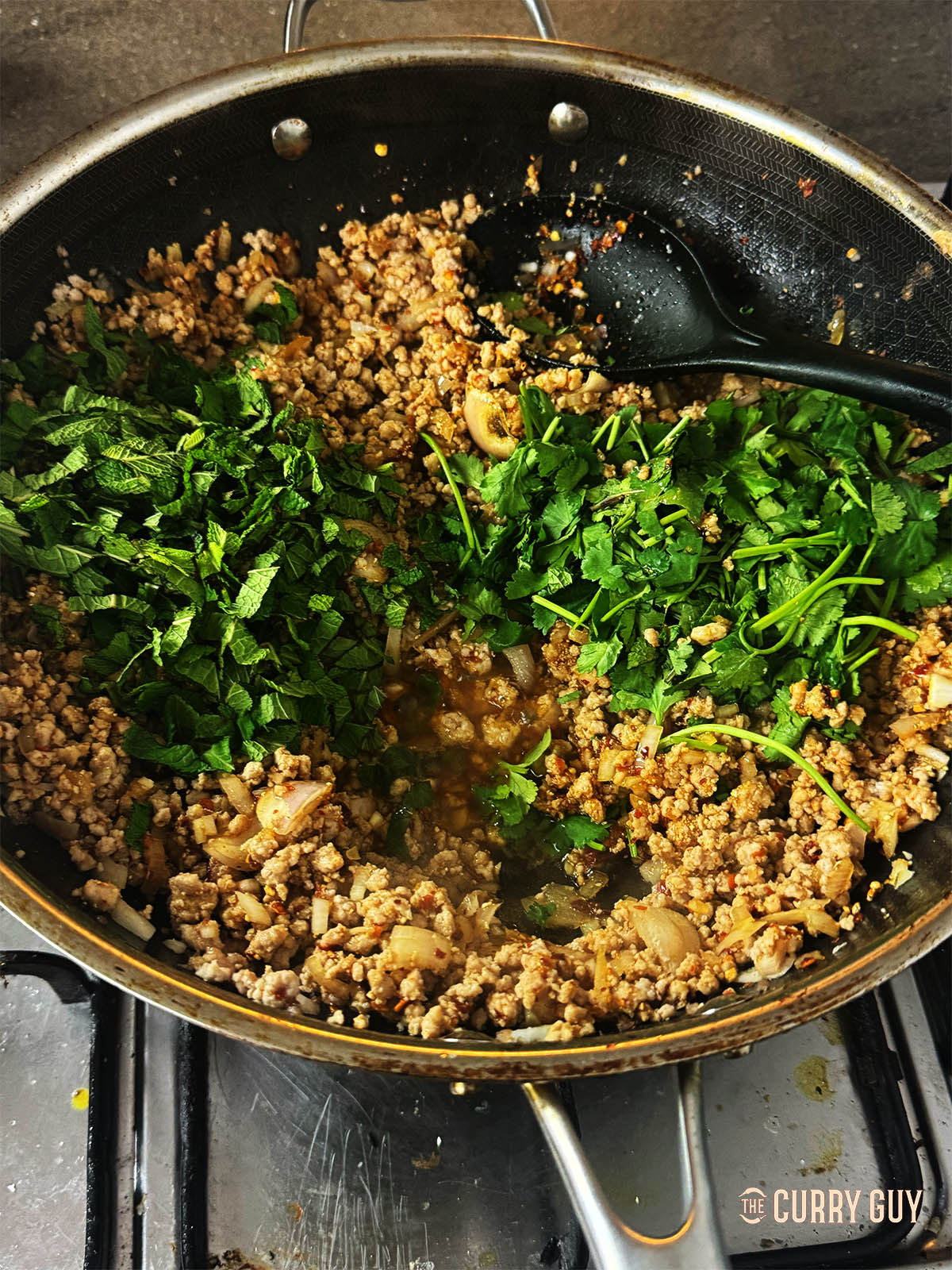 Adding mint, coriander and spring onions to the meat along with the lime juice.