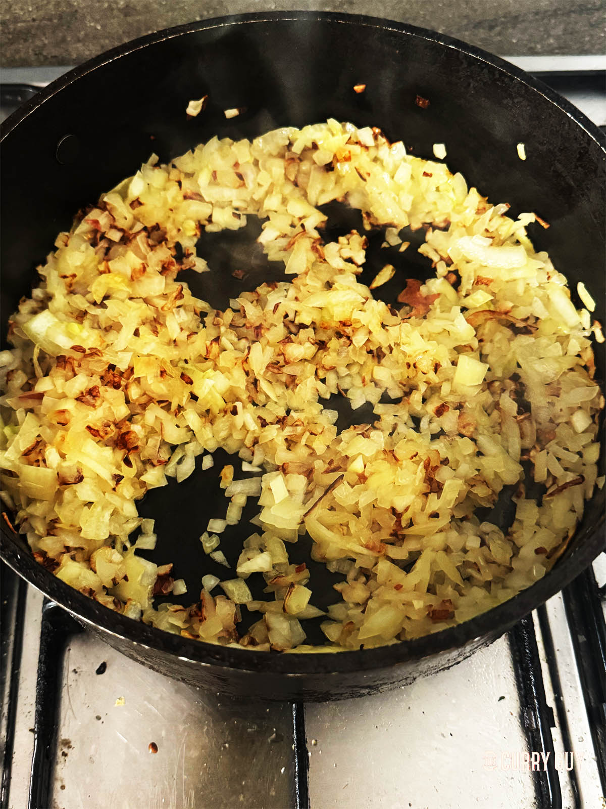 Frying the chopped onions in a pan until golden brown.