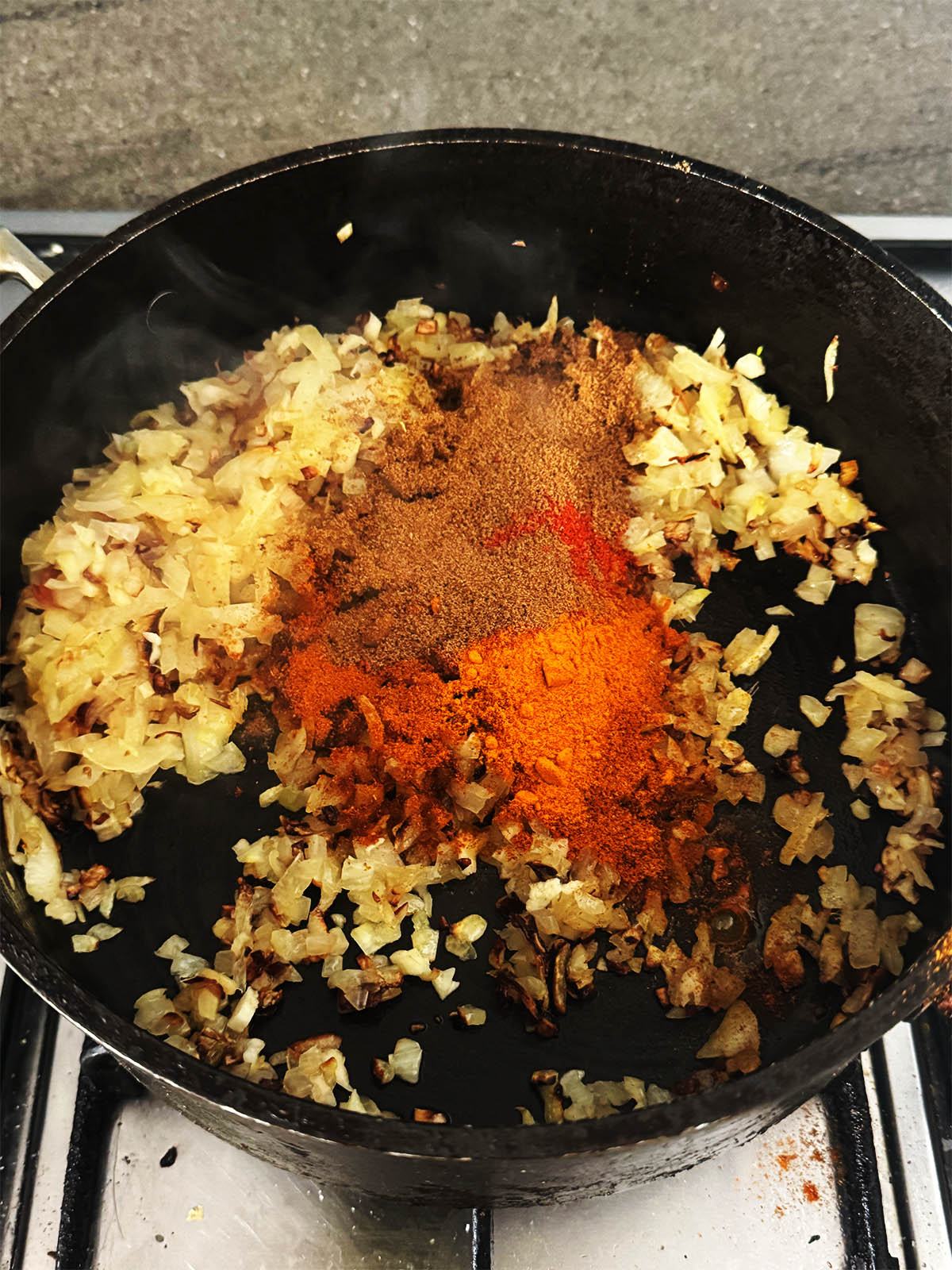 Adding the ground spices to the chopped onions.