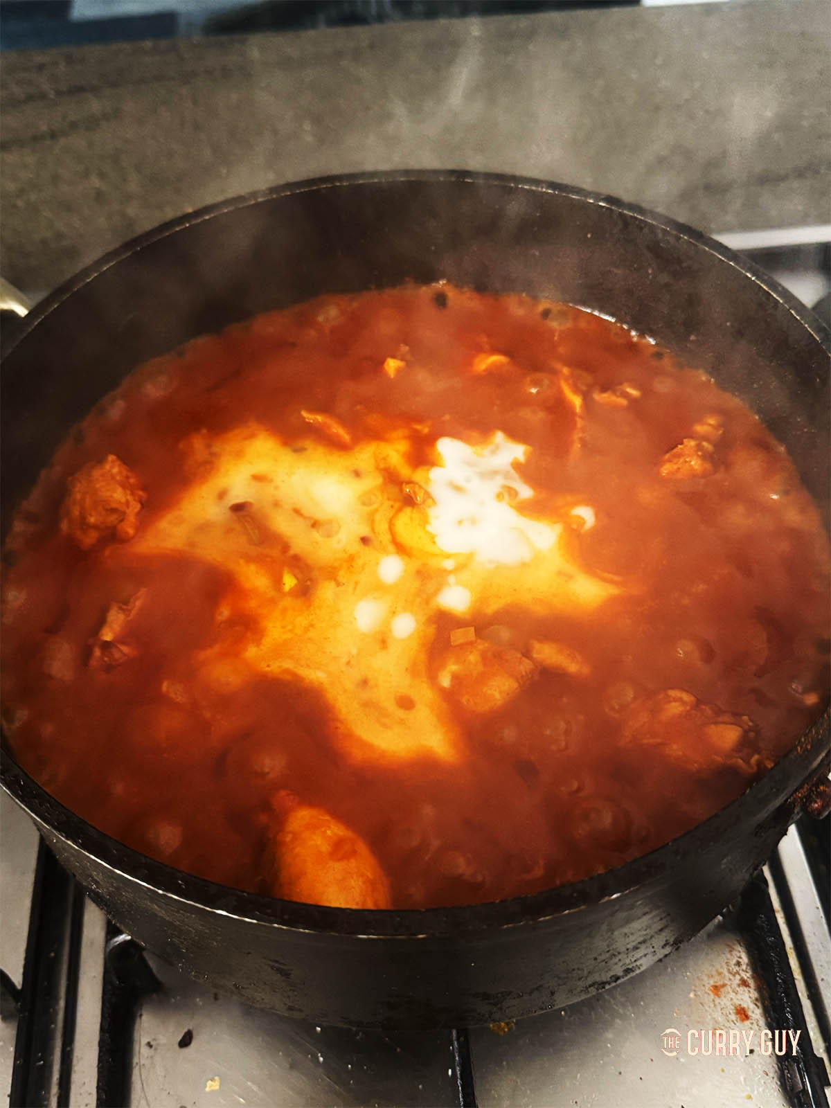 Adding coconut milk to the curry.