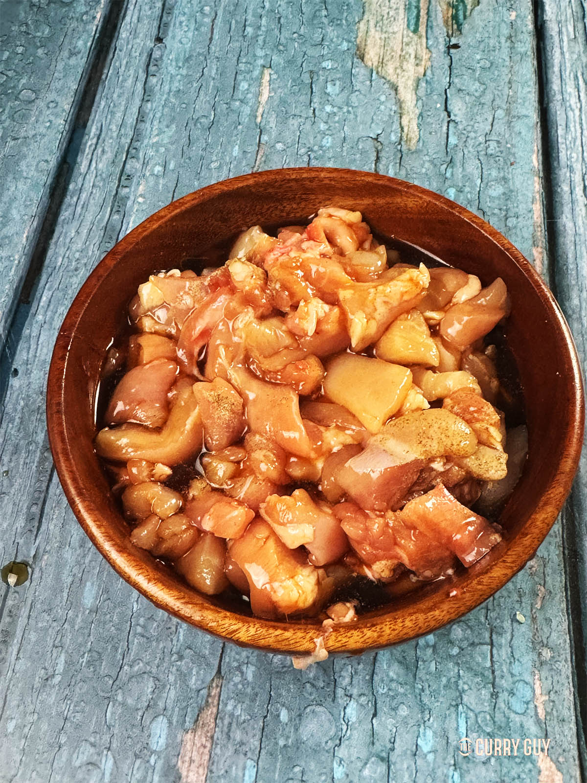 The chicken pieces in a mixing bowl marinating in the marinade ingredients.
