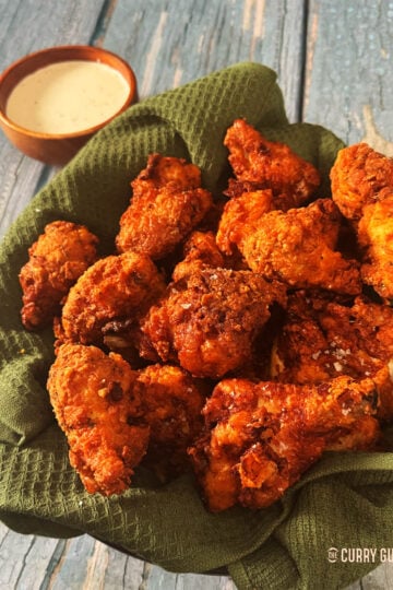 Southern fried chicken in a serving basket next to ranch dressing.