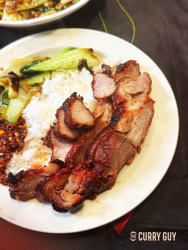 Char Siu on a serving plate with rice, bok choy and Chinese crispy chilli.