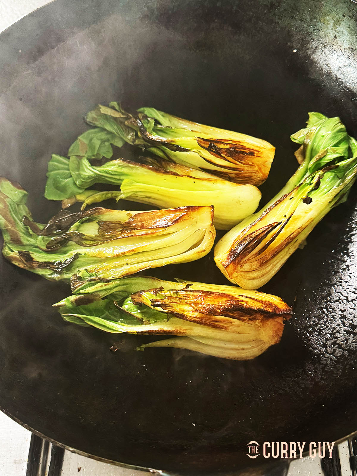 Seared bok choy in a hot wok. 