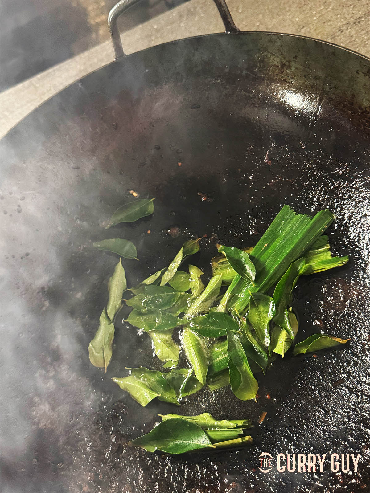 Infusing the curry leaves and pandan leaves in oil.