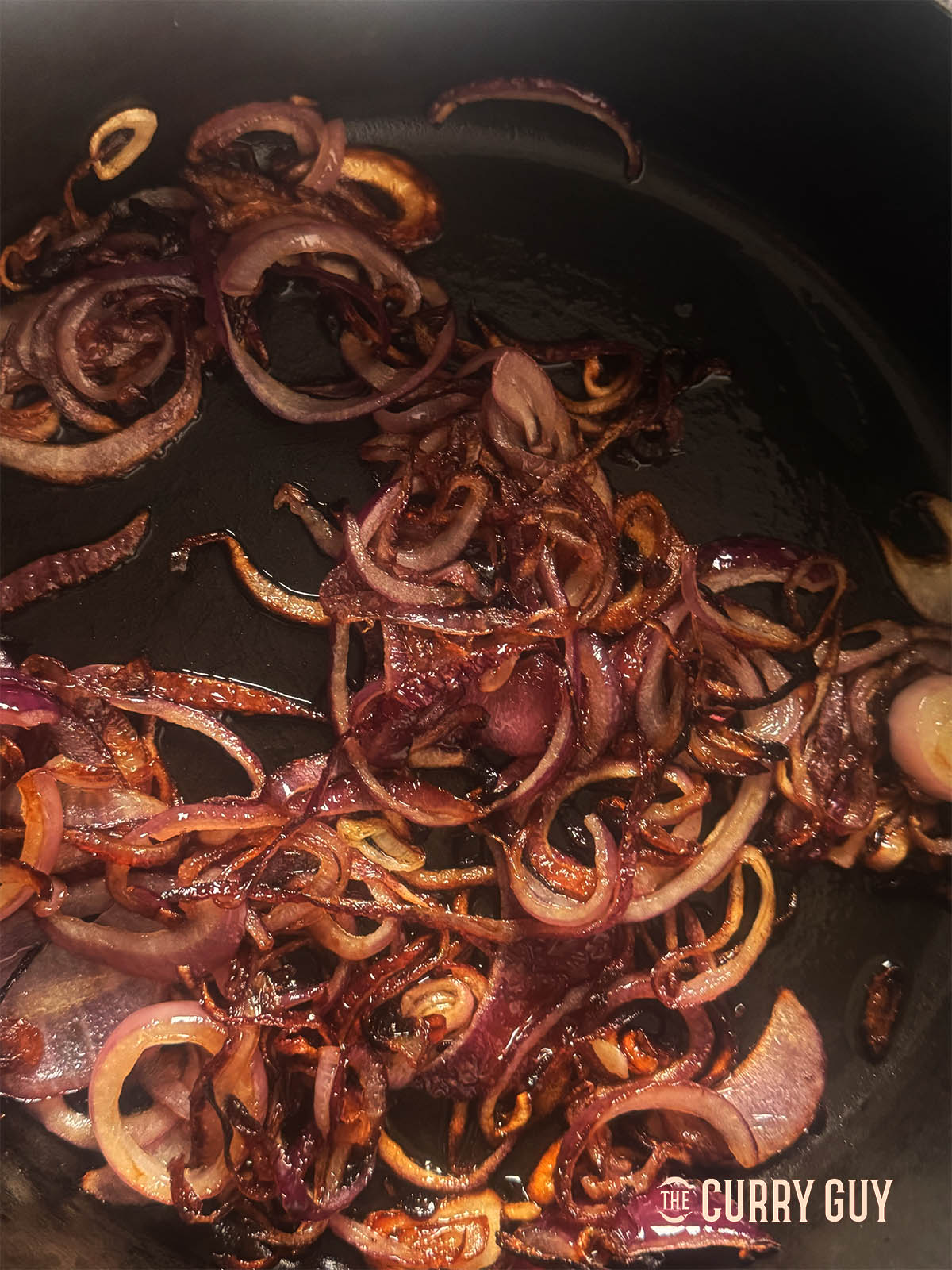 Frying the sliced red onions until golden brown.