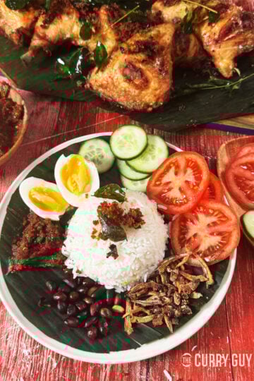 Nasi Lemak on a serving plate next to Malaysian fried chicken