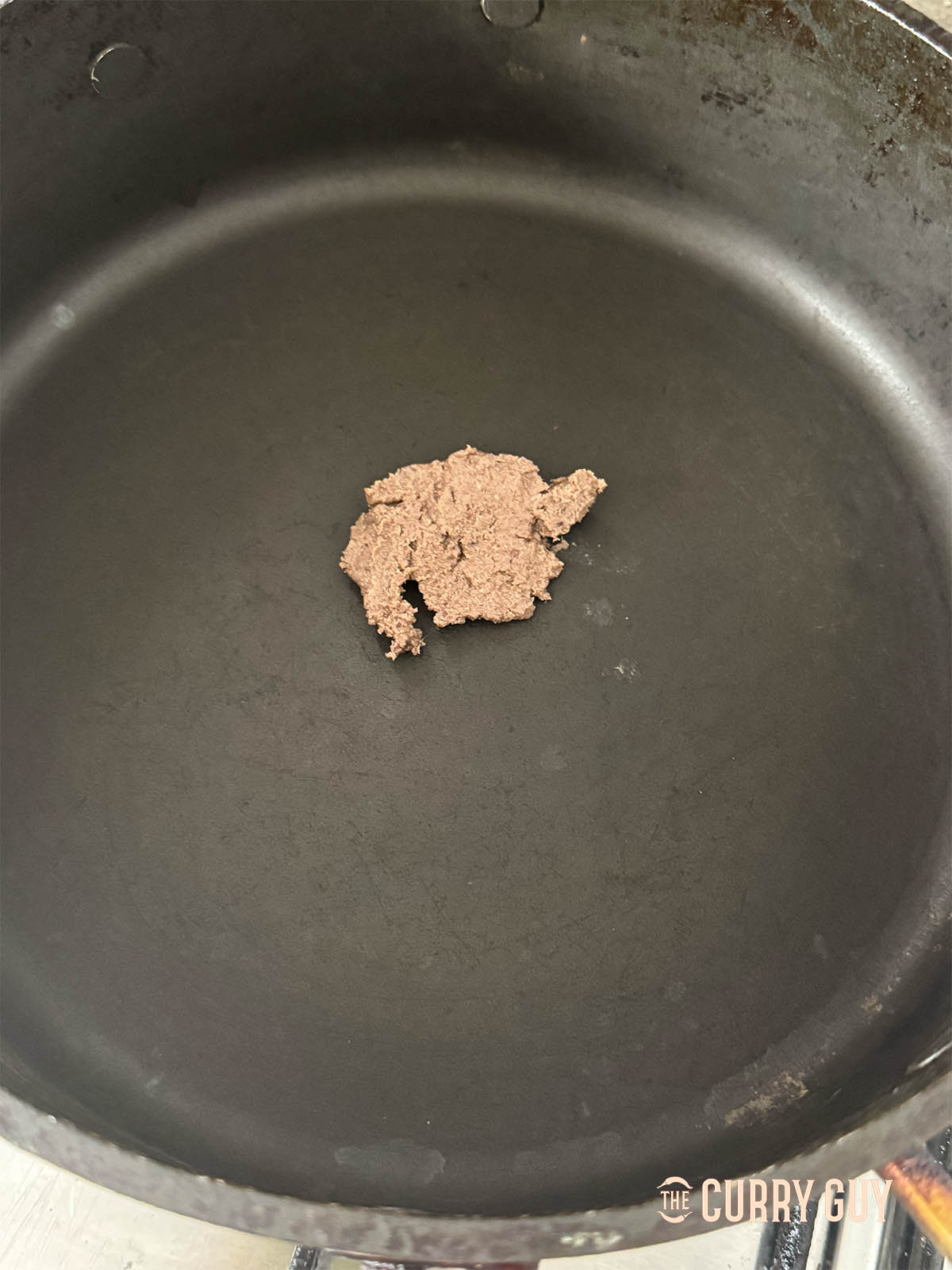 Adding the shrimp paste to the pan.