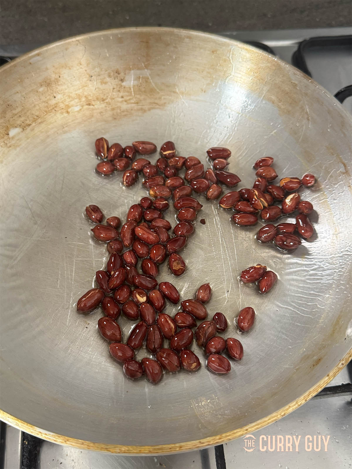 Frying the raw peanuts to brown them and cook through.