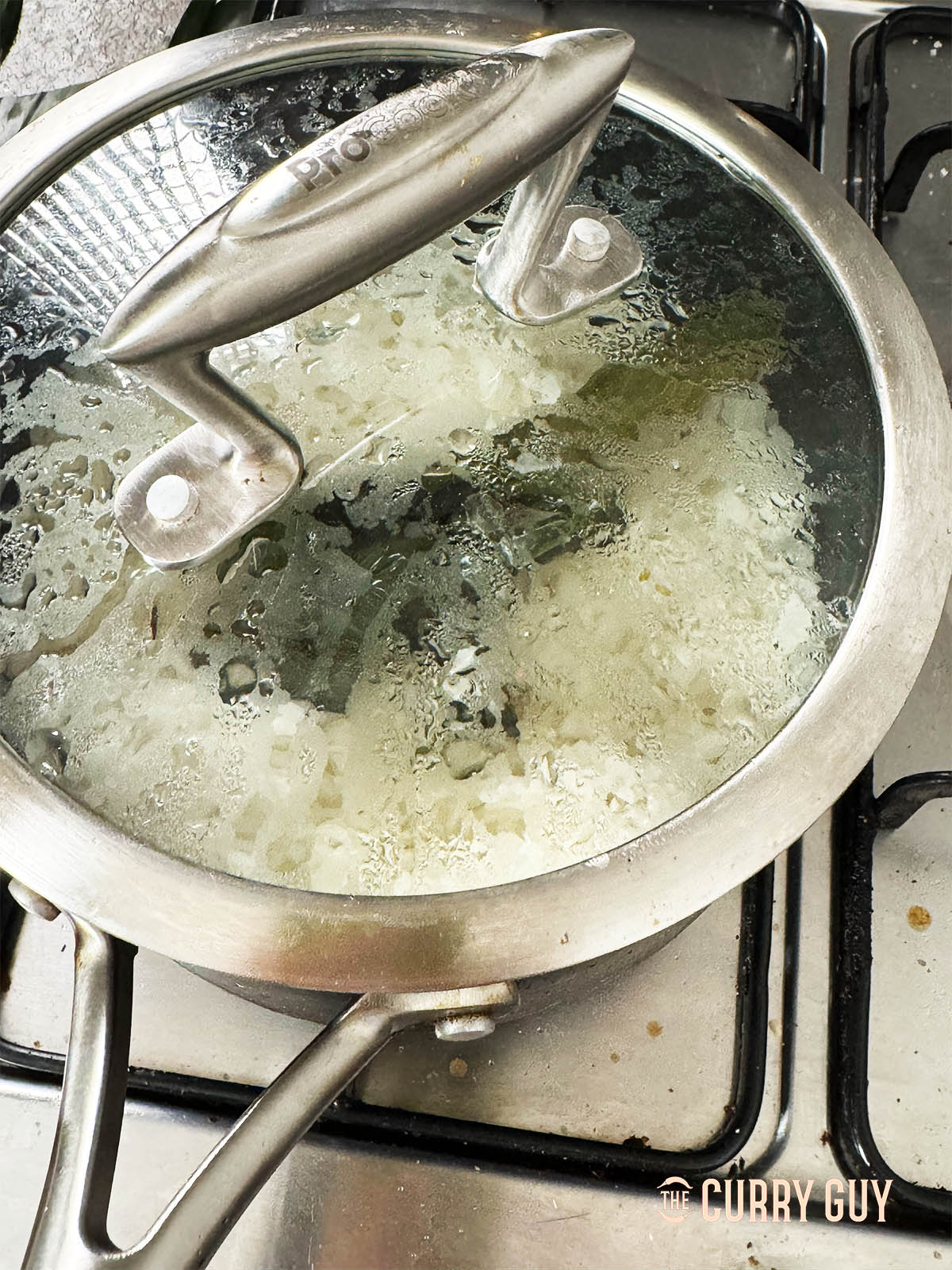 Cooking the rice in water, coconut milk and salt with a pandan leaf for aroma.