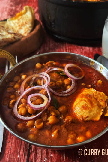 Punjabi Chicken Chole serves topped with slices of red onion.
