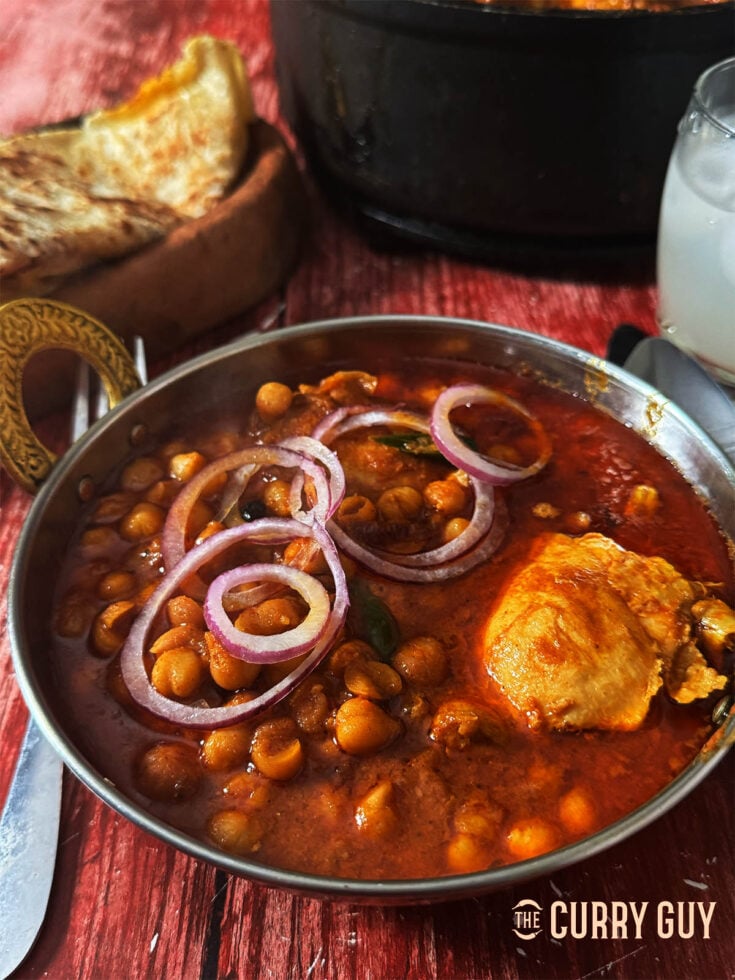 Punjabi Chicken Chole serves topped with slices of red onion.