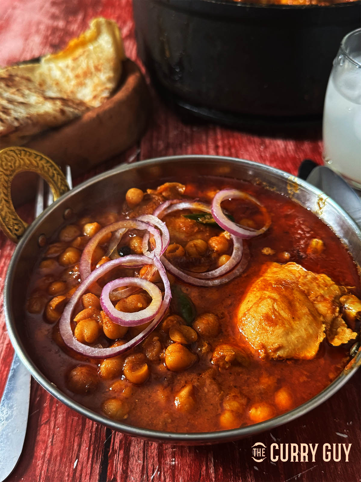 Punjabi Chicken Chole serves topped with slices of red onion.