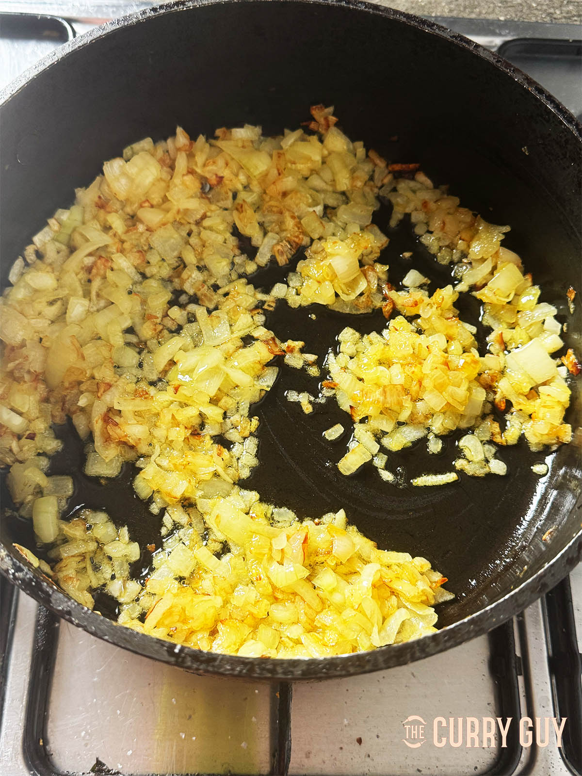 Slowly frying the onions in ghee until golden and soft.