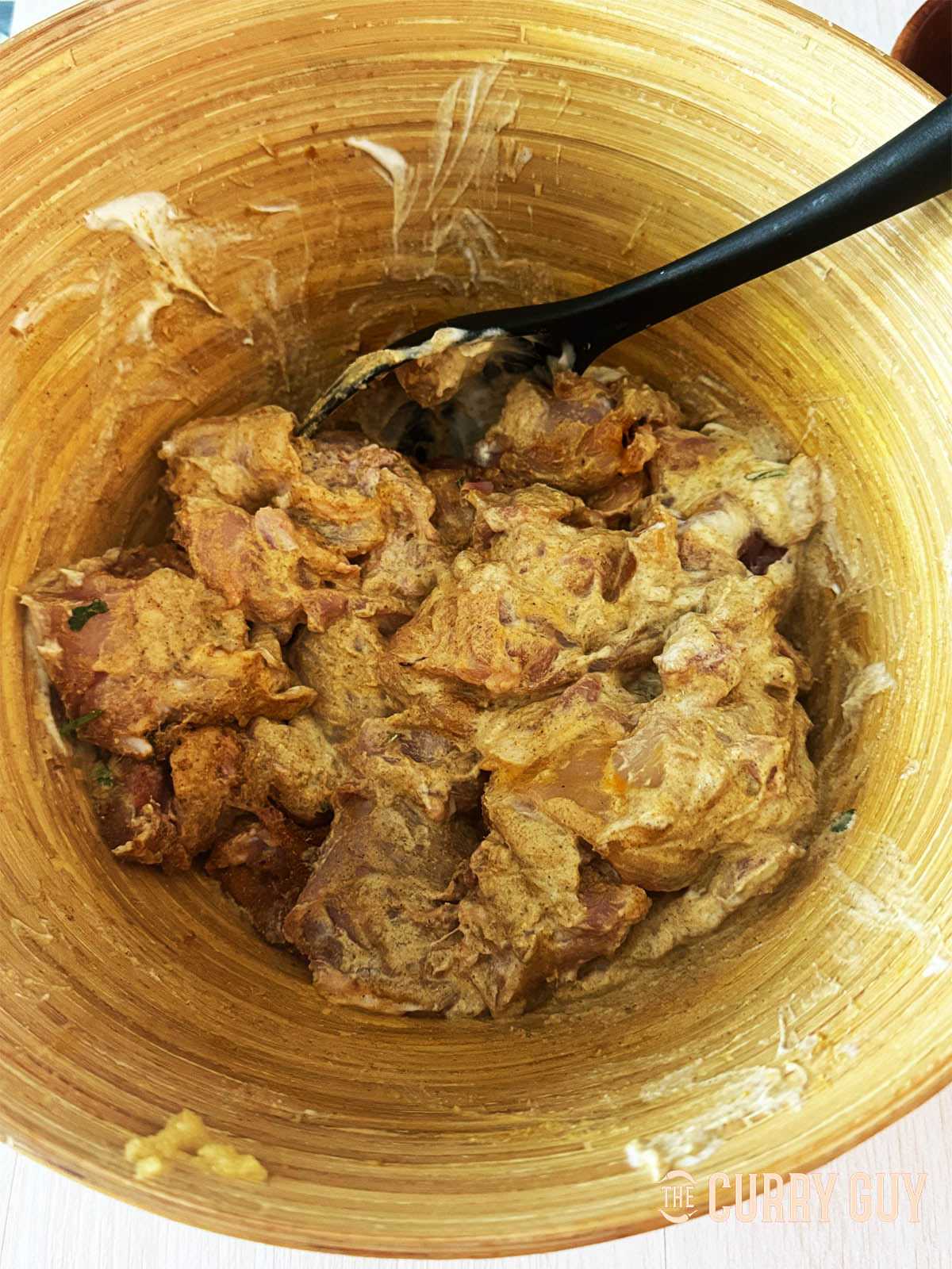 The chicken marinating in a bowl with the yoghurt and other marinade ingredients.
