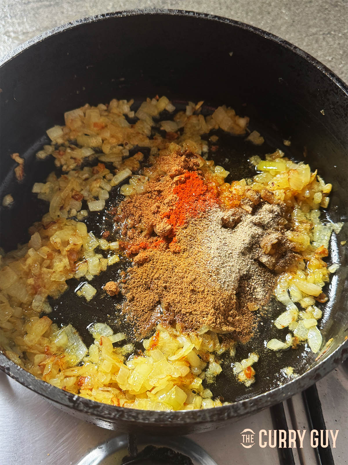 Stirring the garlic and ginger paste into the onions and then adding the ground spices.