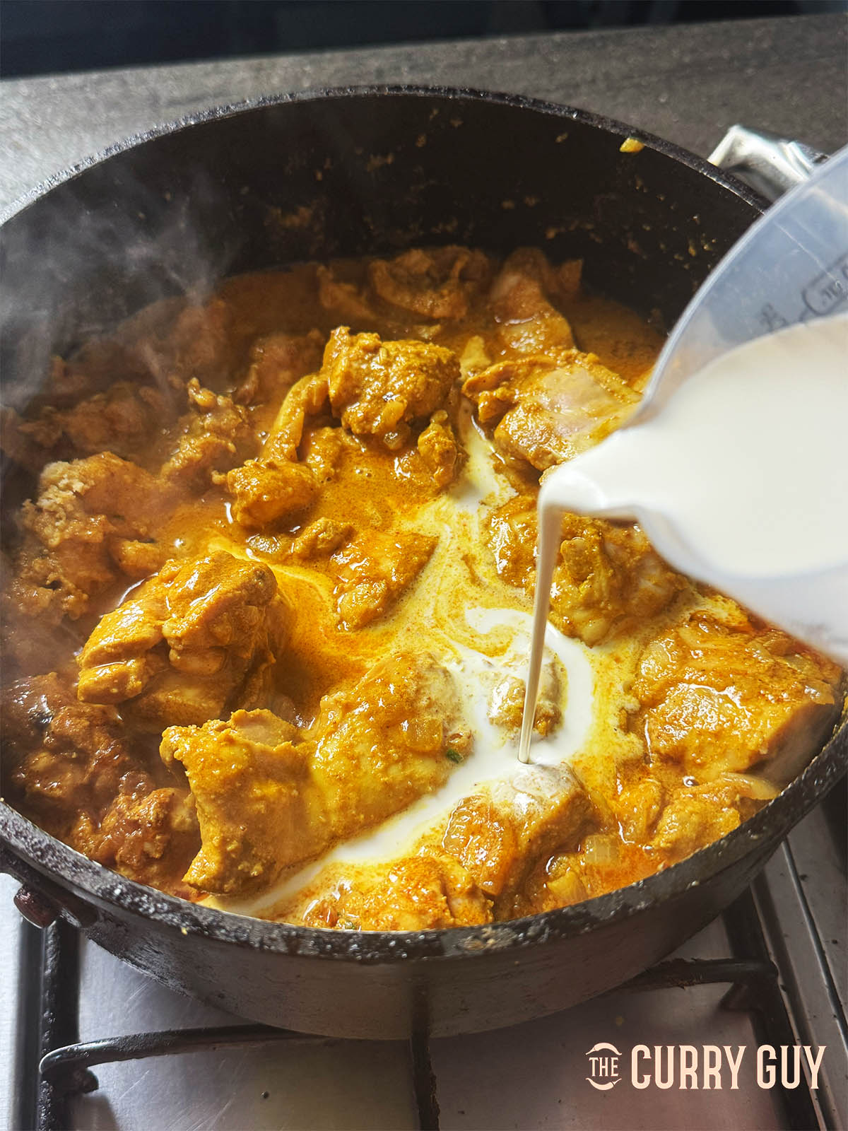 Pouring the cream into the curry.