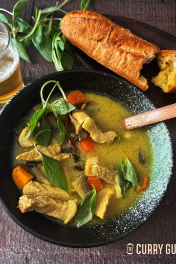 Cambodian green pork curry in a serving bowl with French bread.