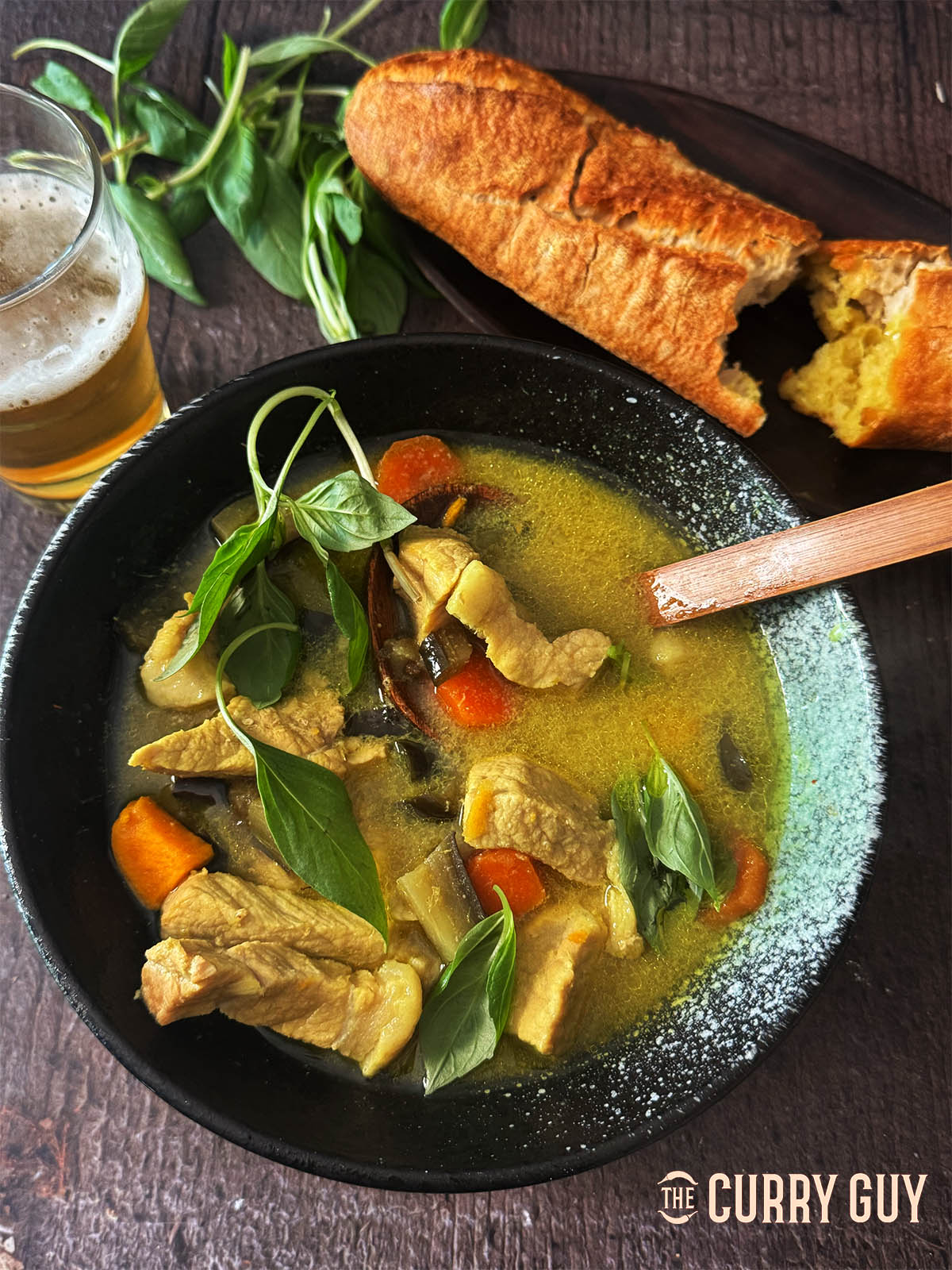 Cambodian green pork curry in a serving bowl with French bread.