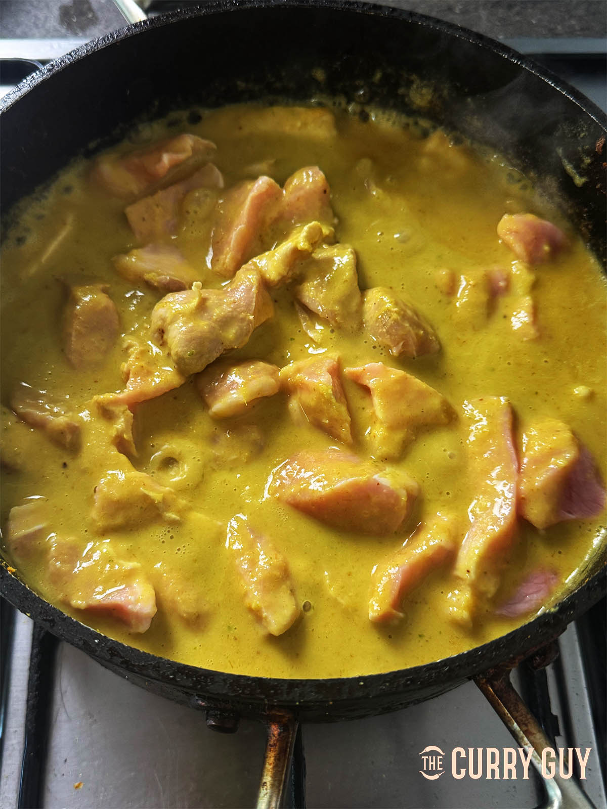 Adding the pork and remaining coconut milk and stock or water to the pan.
