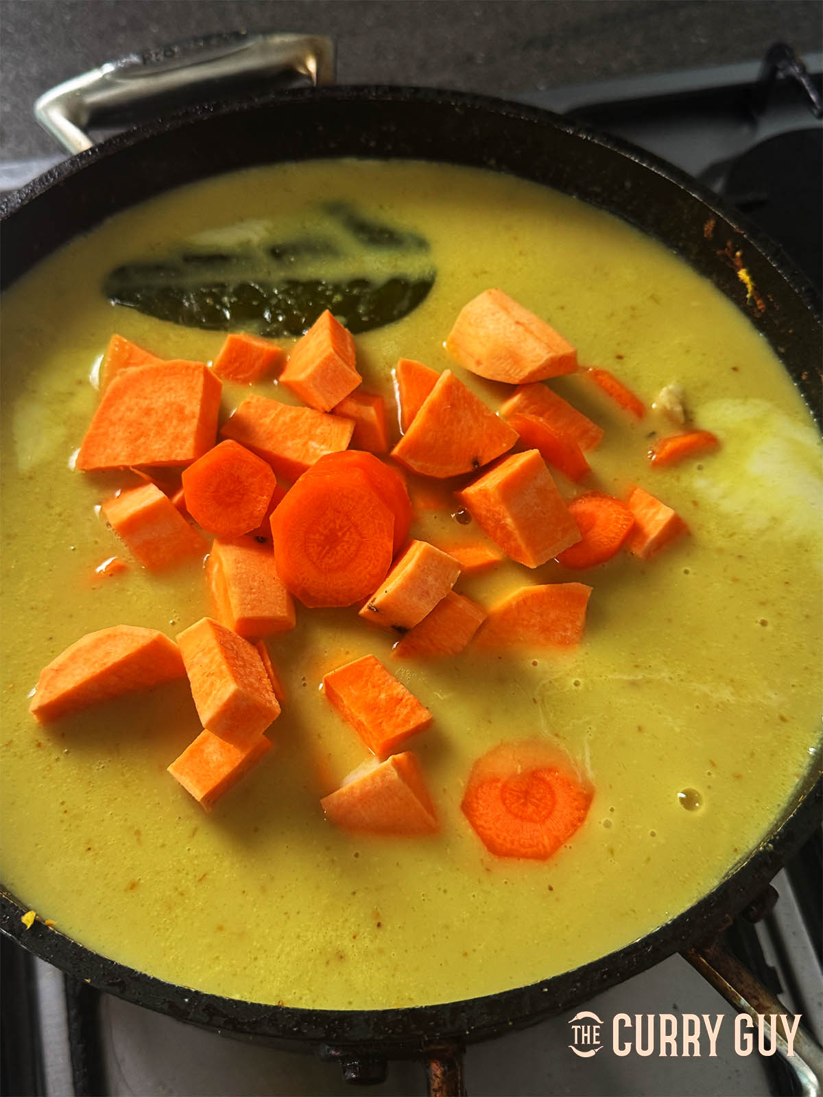 Adding the carrots and sweet potato to the pan.