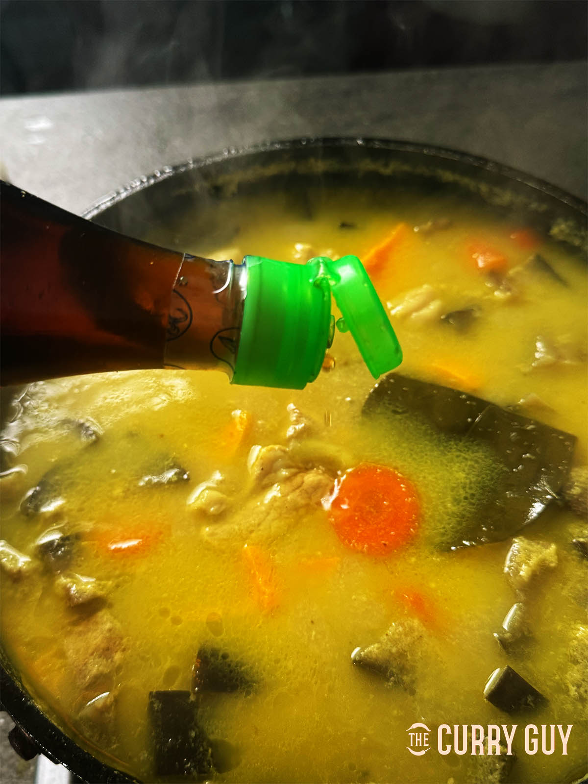 Pouring fish sauce into the curry for seasoning.