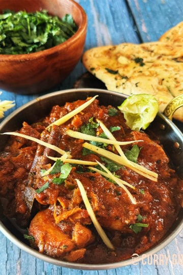 Chicken Adrak curry in a serving bowl, served with naans.