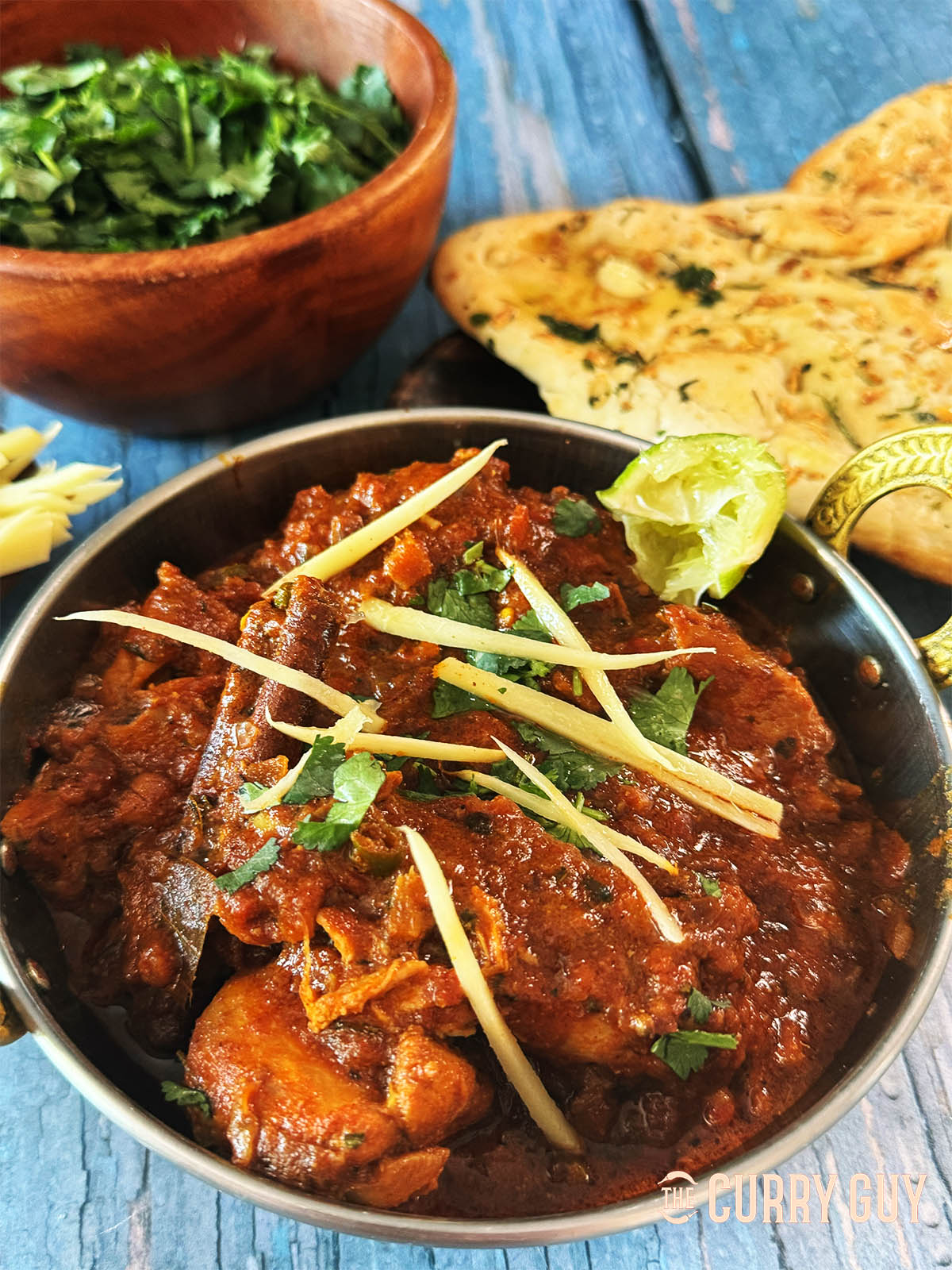 Chicken Adrak curry in a serving bowl, served with naans.