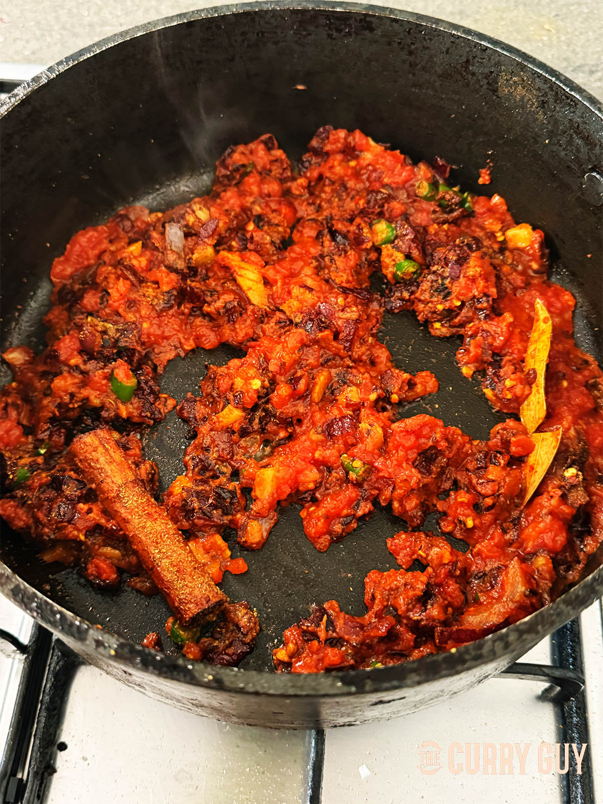 Adding the tomatoes and stirring them into the onion mixture.