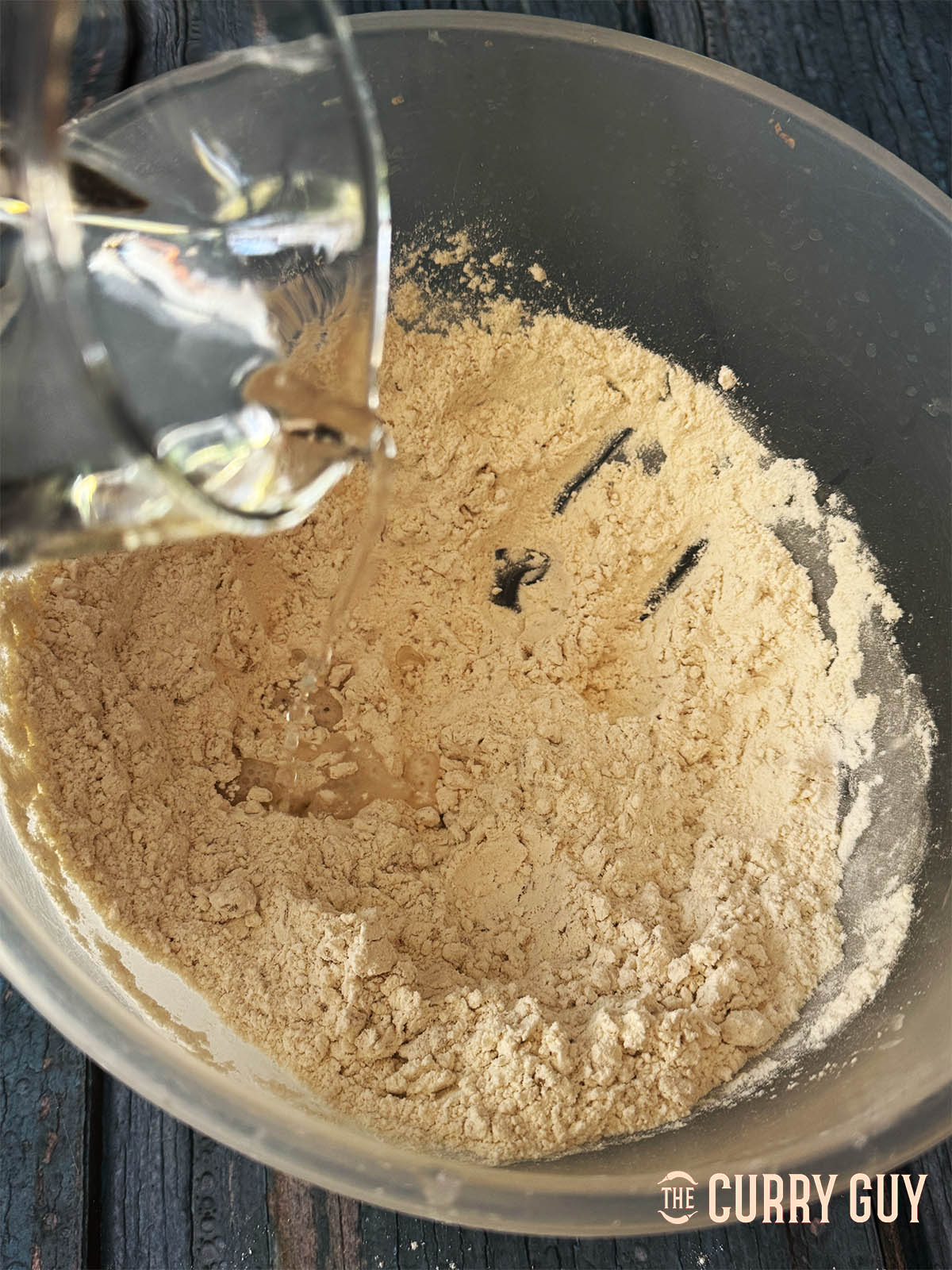 Gradually and slowly adding water to form a firm dough.