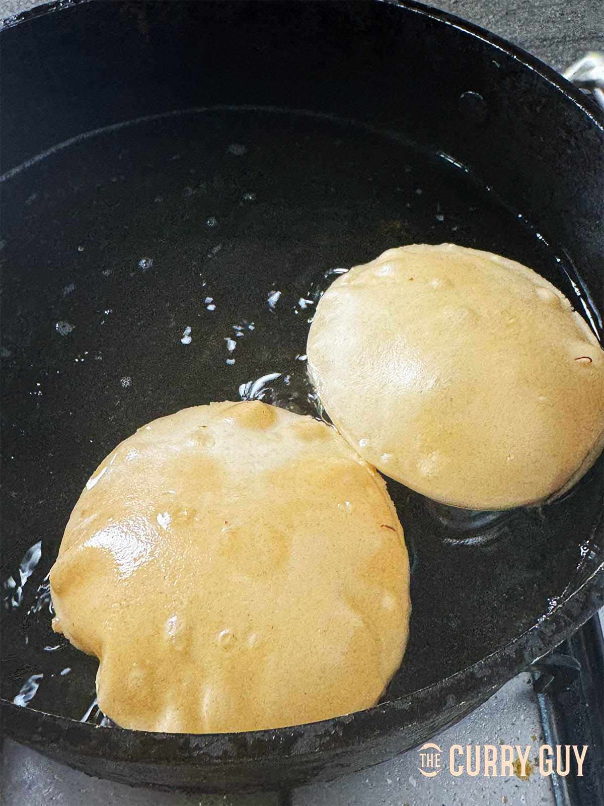 Fresh puffed puris floating in the oil.
