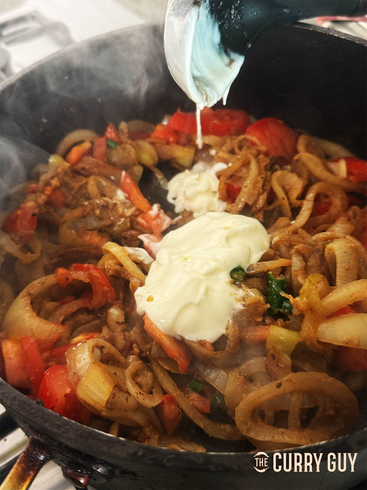 Stirring in the yoghurt one tablespoon at a time.