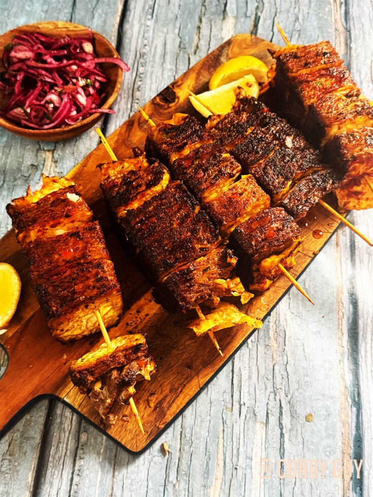 Beef lavash kebabs served on a serving board with onion salad.