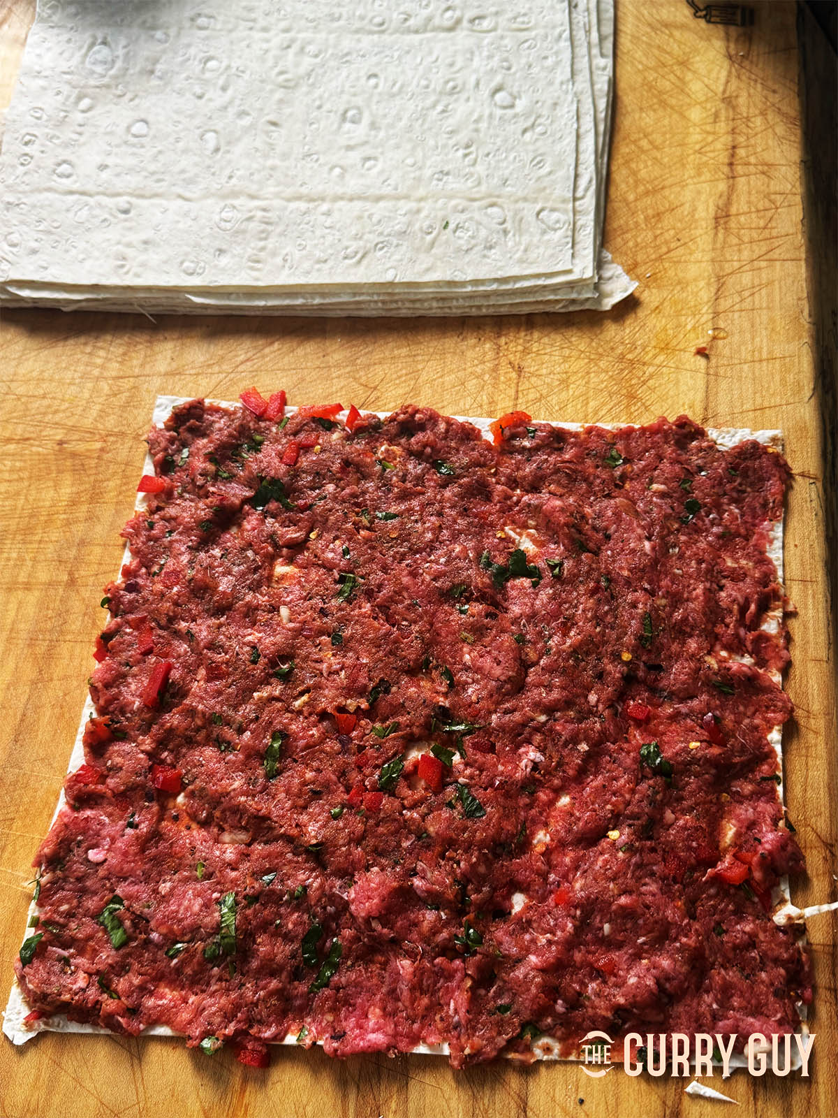 Spreading some of the meat mixture over a lavash square.
