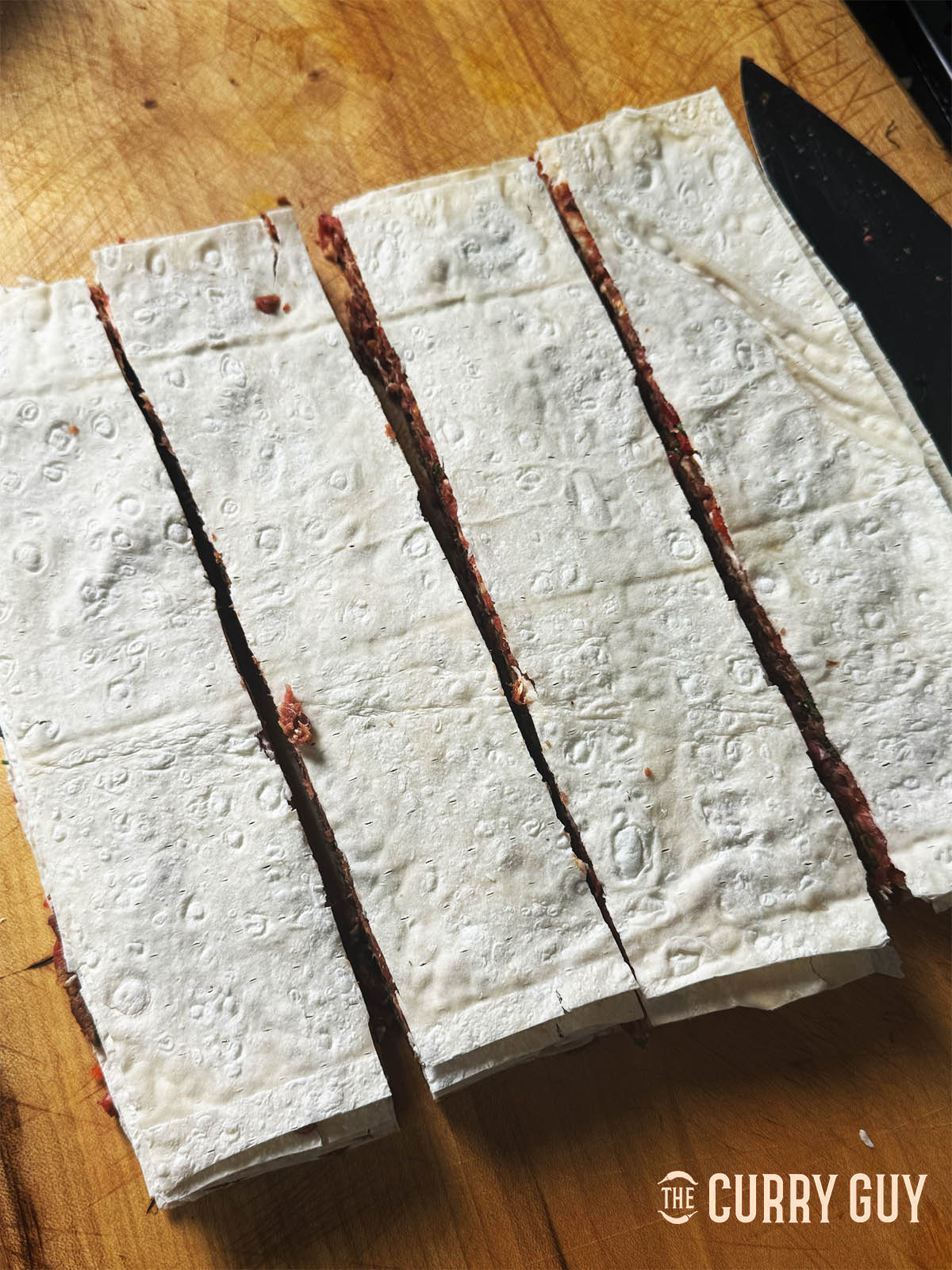 Slicing the lavash and meat stacks into strips.