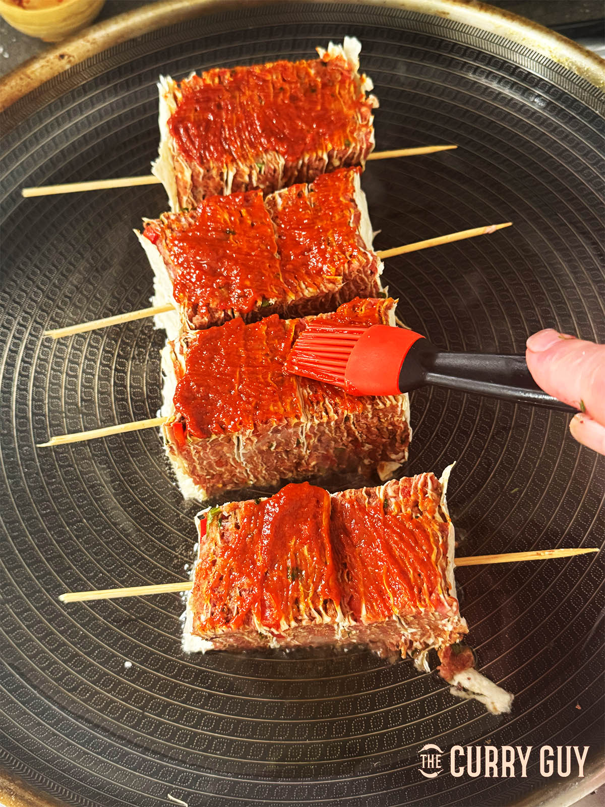 Basting the lavash kebabs with the pepper sauce.