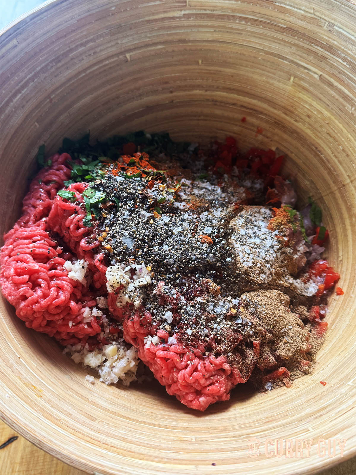 The meat and spices in a large mixing bowl, ready to mix and combine for use.