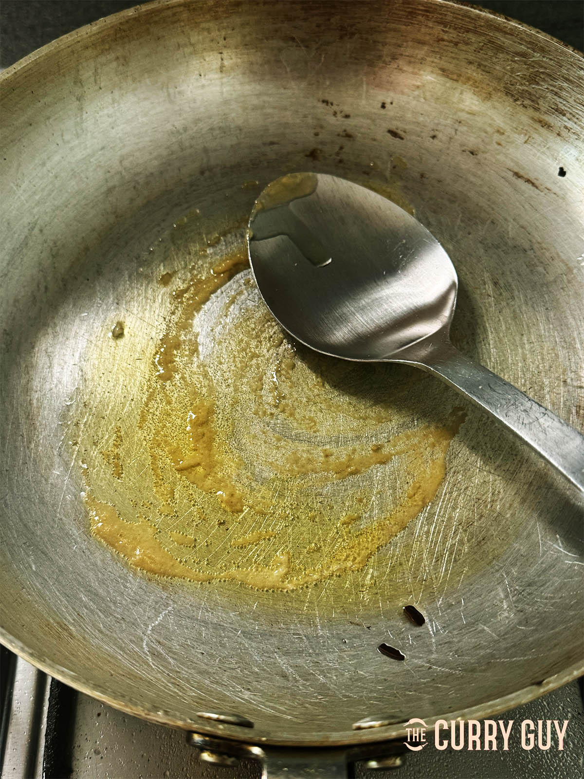 frying the garlic and ginger paste in a pan.