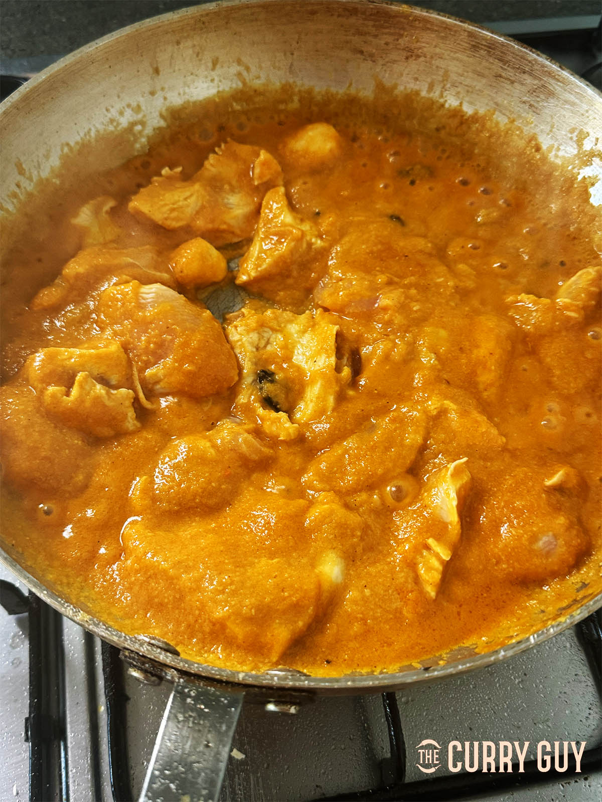 Adding the chicken to the pan to cook through in the hot sauce.