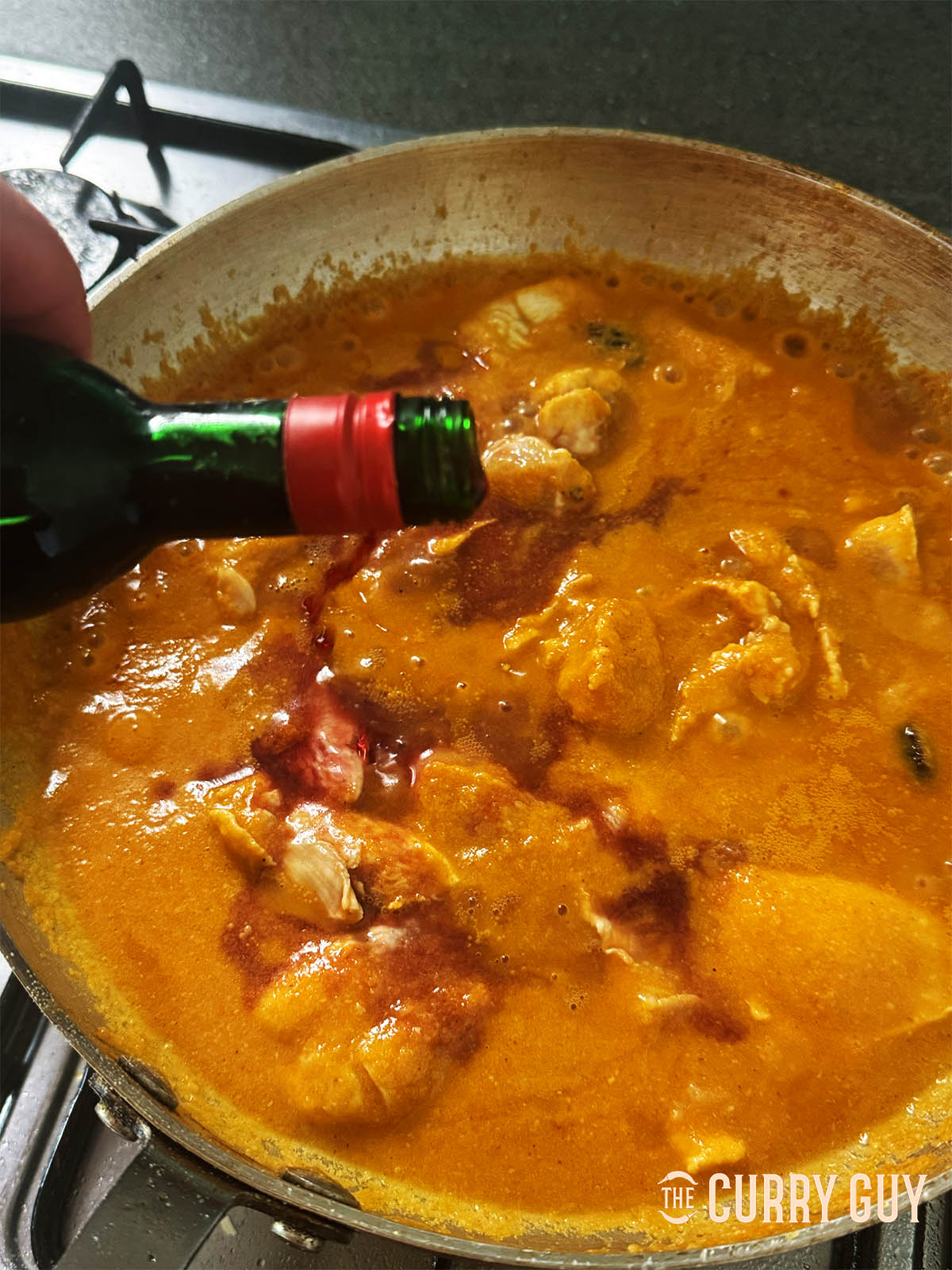 Adding the red wine to the simmering sauce.