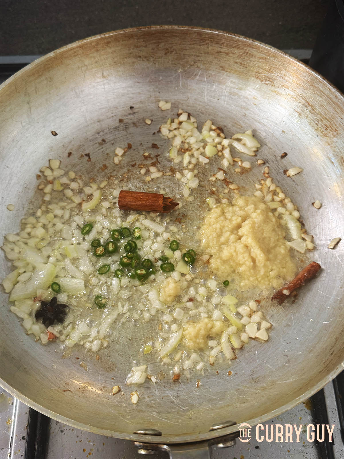Adding the onion, garlic and ginger paste and chillies to the pan.