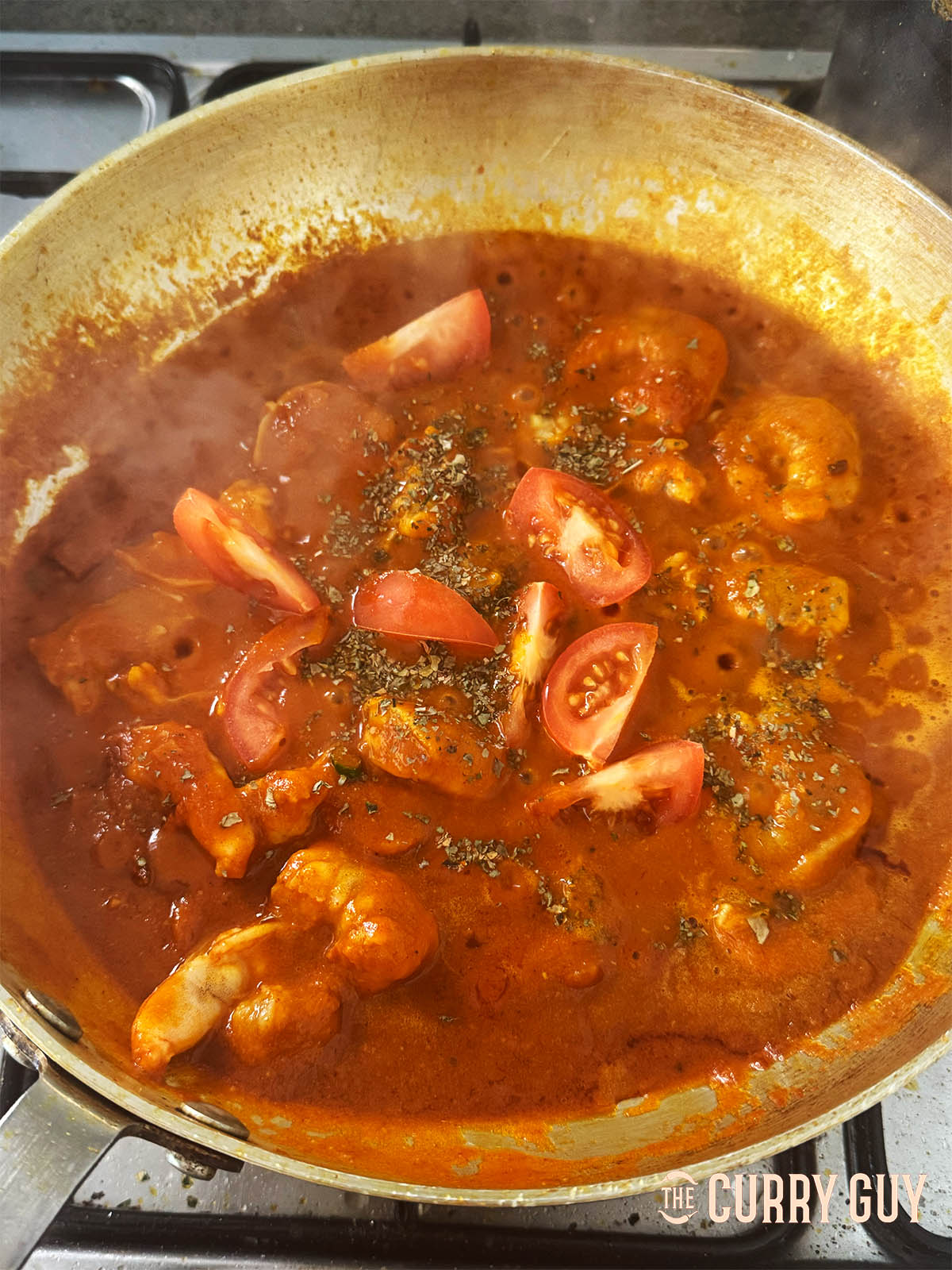 Adding the quartered tomatoes and kasoori methi to the curry.
