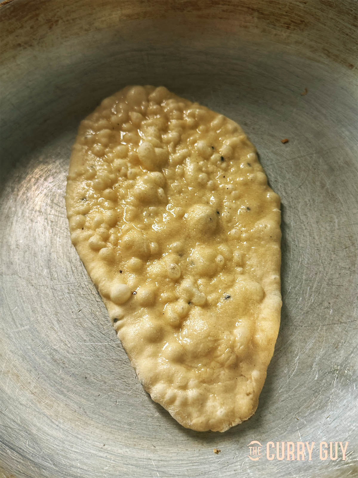As the naan cooks, bubbles will appear on top like this.